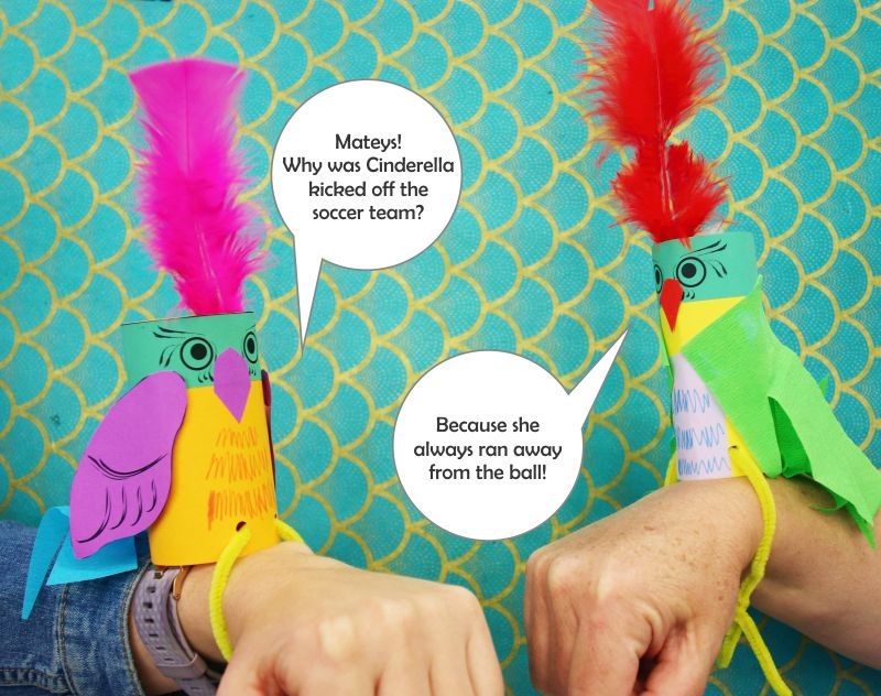Kids craft example of two parrots made from coloured cardboard and paper, sitting on arms