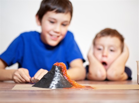 Two young children playing with a volcano experiment
