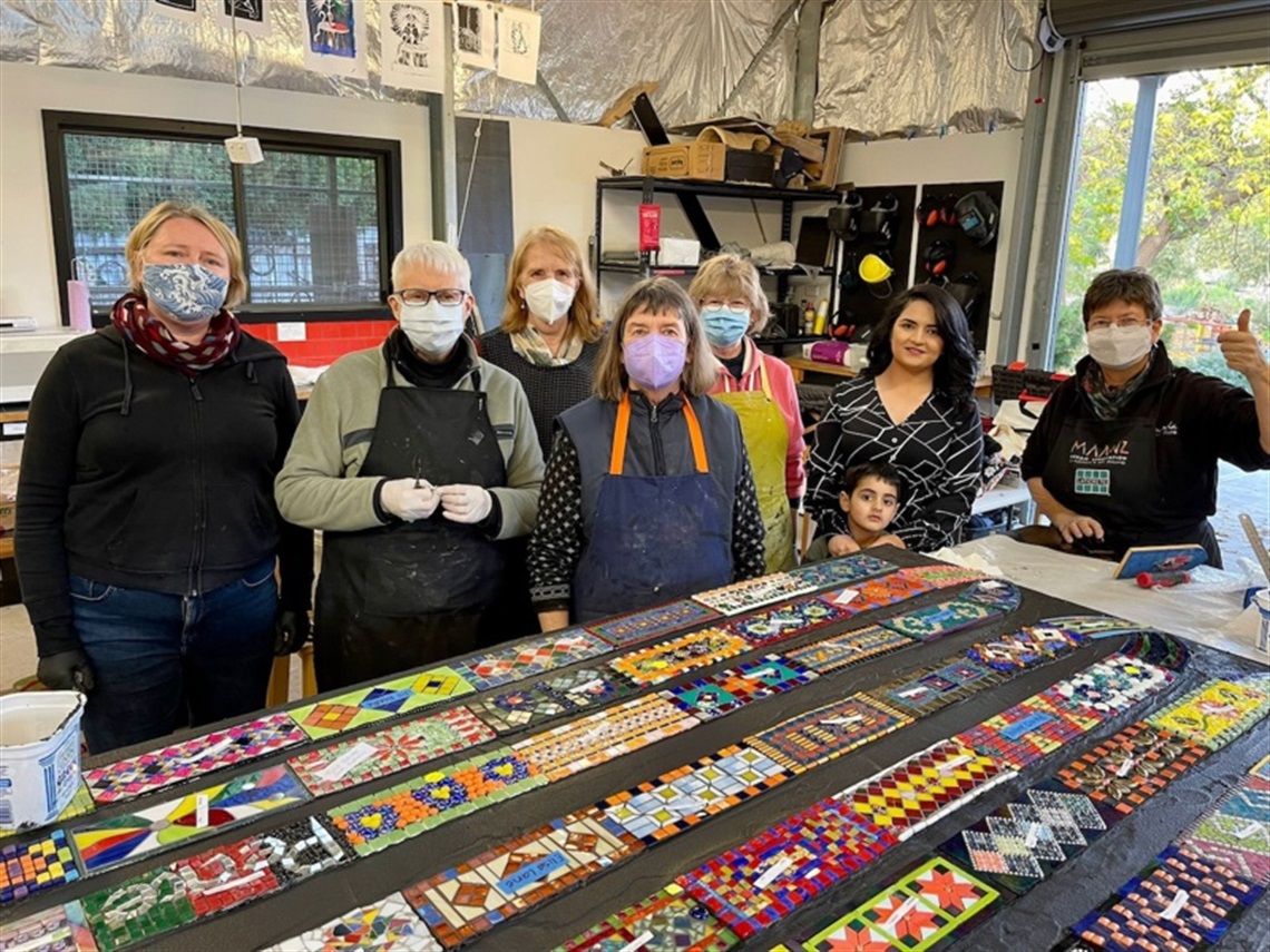 People clustered around a mosaic scarf artwork