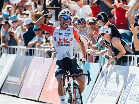cyclist celebrating stage finish with crowd behind barrier
