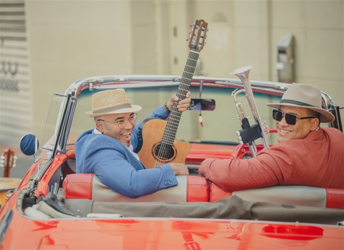 A couple of guys with musical instruments in a red car