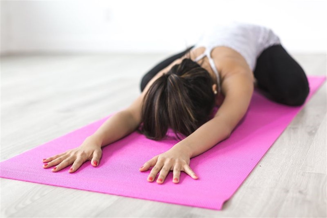 woman stretched out in yoga pose on pink mat 