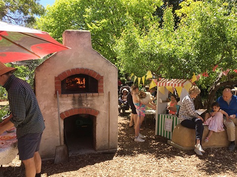People using an outdoor pizza oven in garden setting