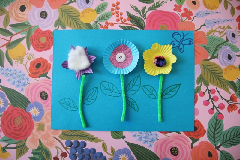 Flower craft made of cardboard, patty pans, pipecleaner, buttons and pompoms.