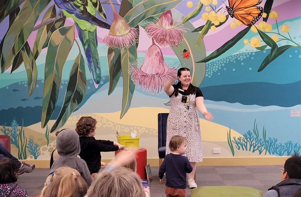 Storyteller in front of children doing actions