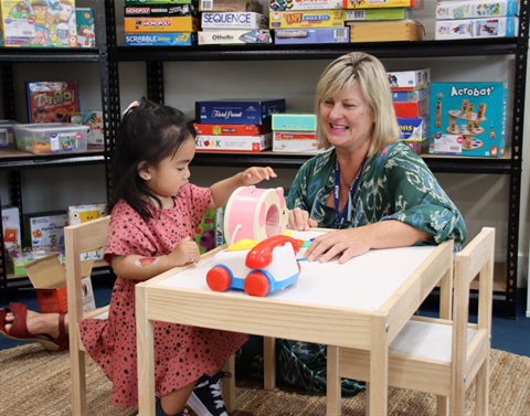 Toy Libraries staff member playing with a young child at a table