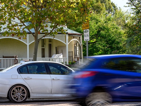 white sedan parked in front of house and a 4-hour-parking-zone-sign