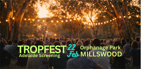 A lot of people in a park at dusk, with lights above them hanging in the trees, and text that reads 'Tropfest'