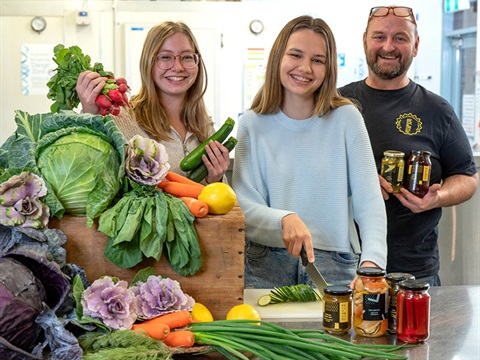people in pickling workshop with fresh vegetable display