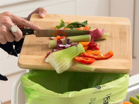 scrapping food scraps into a kitchen caddy